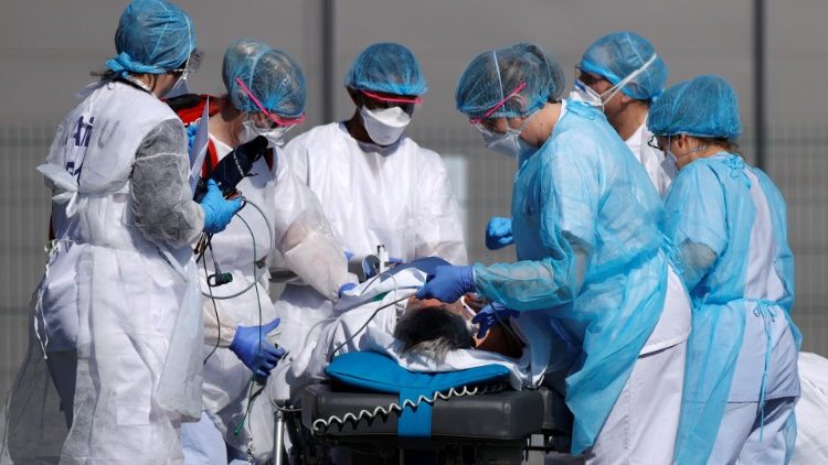 French rescue team wearing protective suits carry a patient on a stretcher from Mulhouse hospital