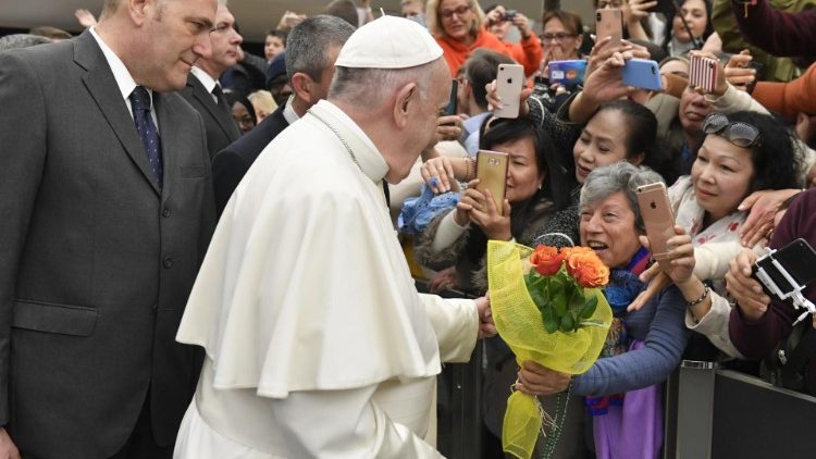 A woman gives Pope Francis a bouquet of flowers at the General Audience